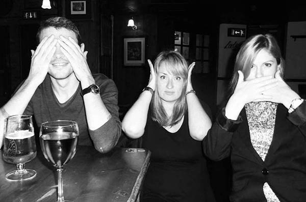 Three people in a pub doing 3 Wise Monkeys