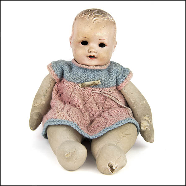 Vintage composition doll with cloth body wearing pink and blue knitted dress