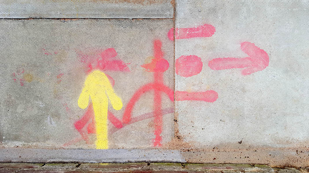 Pavement markings - spray painted squiggles on paving stones - Yellow arrow and red squiggles