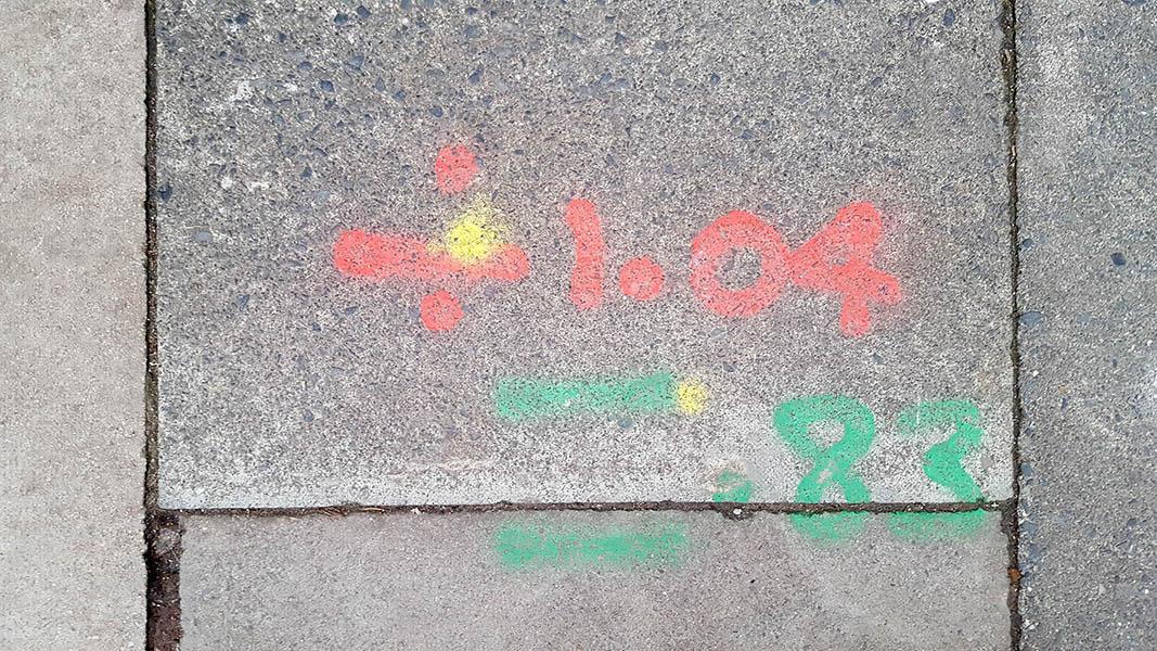 Pavement markings - spray painted squiggles on paving stones - Red and green lines and numbers