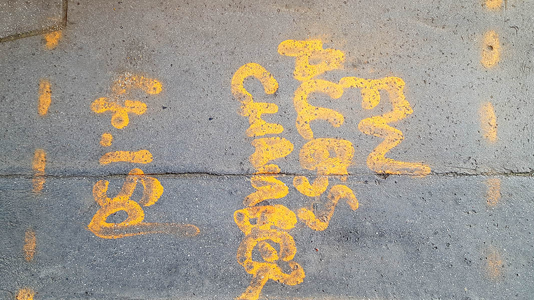 Pavement markings - spray painted squiggles on paving stones - Yellow letters and dashed lines