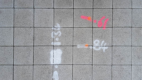 Pavement markings - spray painted squiggles on paving stones - Pink and white numbers