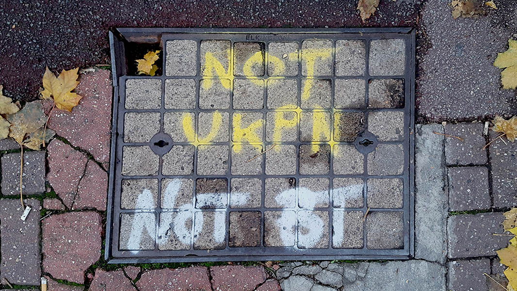 Pavement markings - spray painted squiggles on broken brick pavement - Large rectangular Elkington access panel with yellow NOT UKPN and white NOT BT