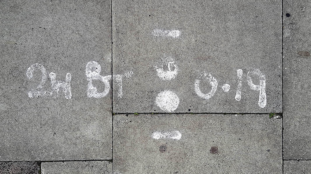 Pavement markings - spray painted squiggles on paving stones - Two white dots sandwiched between horizontal lines. 2W BT to the left and 0.19 to the right